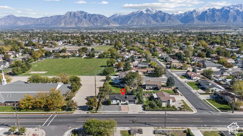 Aerial perspective featuring a single-story residence with an attached garage, paved driveway, and mountain backdrop