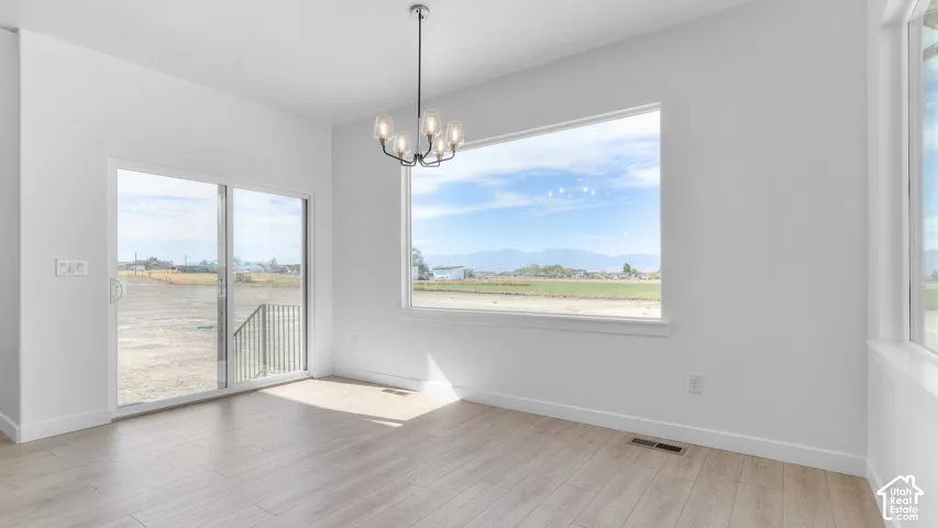 Bright interior featuring wood-finish flooring, a contemporary five-light chandelier, a large picture window, and glass sliding doors