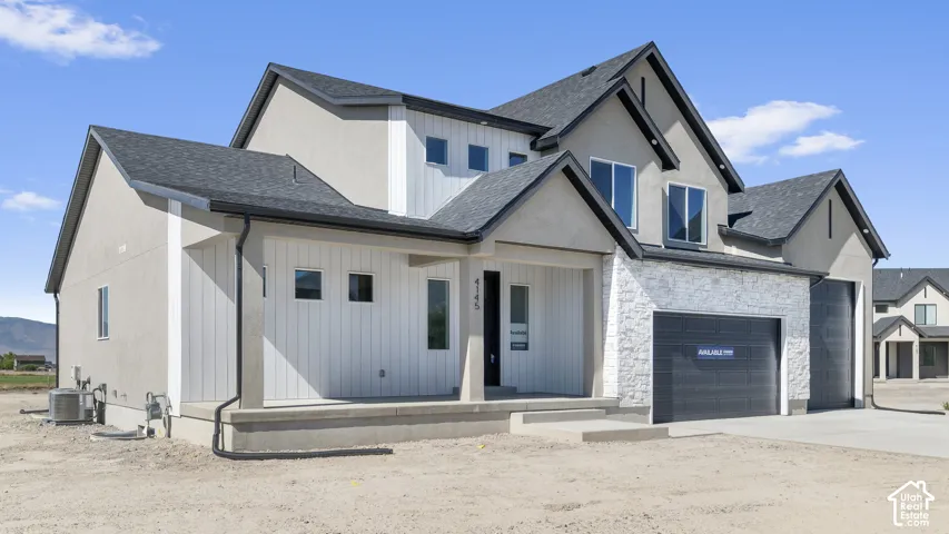 Modern multi-gabled exterior featuring stucco siding, vertical board-and-batten accents, white stone masonry, and a three-car garage
