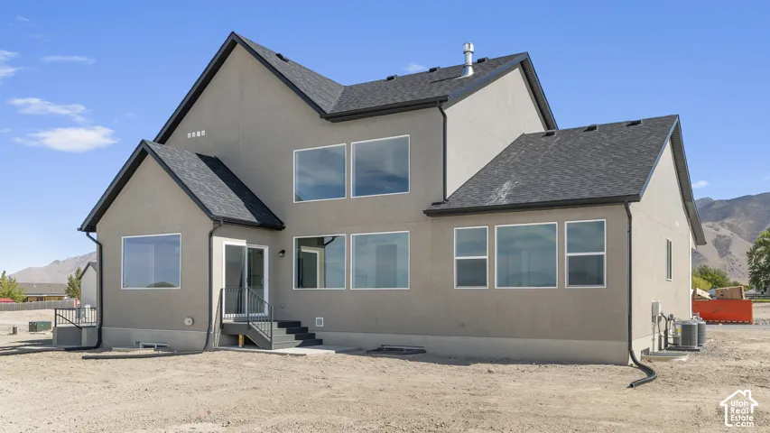 Two-story exterior featuring a neutral stucco finish, multi-gable roofline, numerous large picture windows, and metal staircase