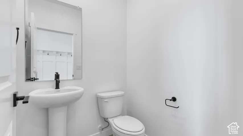 Pedestal sink with a matte black faucet, wall-mounted mirror, and matte black hardware