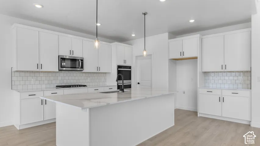 Kitchen featuring white cabinetry, stone-surface countertops, center island, subway tile backsplash, and stainless steel built-in appliances