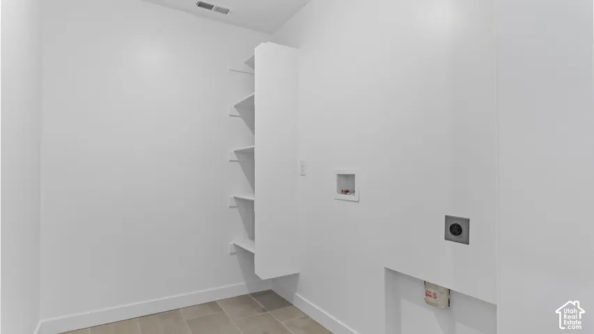 Laundry area featuring tile flooring, built-in shelving, and dedicated hookups for washer and dryer units