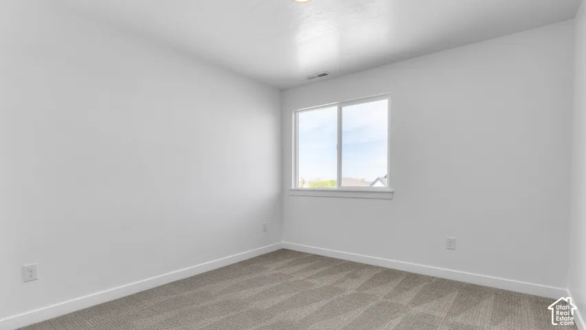 Neutral-toned carpeted flooring, white wall finish, and a sliding glass window