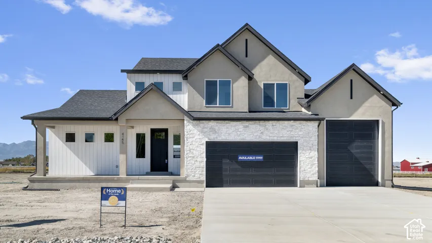 Modern exterior featuring vertical white panel siding, stone veneer accents, dark metal garage doors, multi-gabled roofline, and a concrete driveway