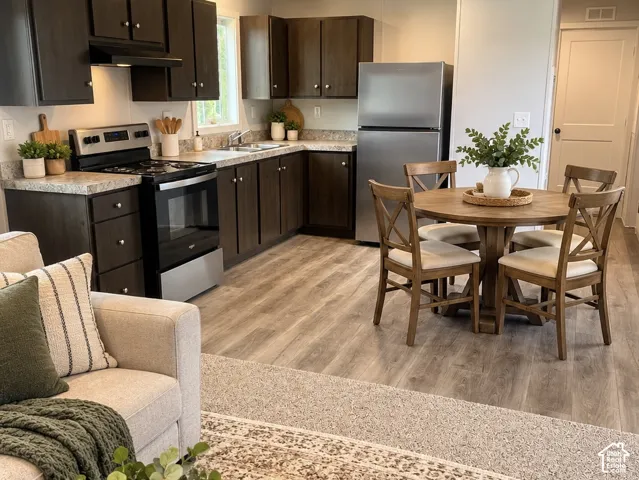 Kitchen featuring dark-finish cabinetry, solid-surface countertops, stainless steel appliances, and wood-finish flooring. AI Staging.