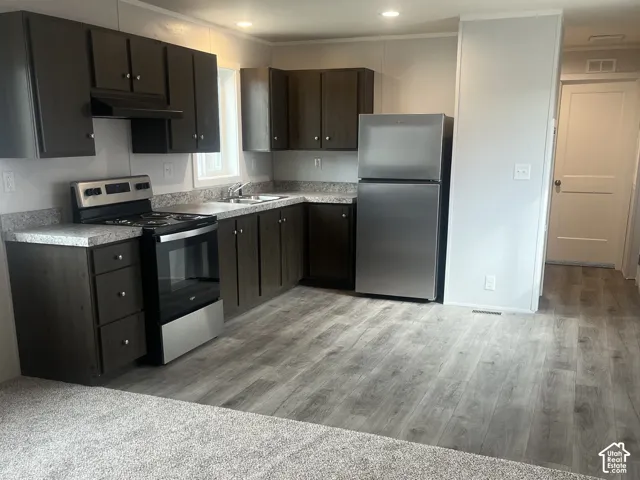 Kitchen featuring dark wood-finish cabinetry, stone-pattern laminate countertops, stainless steel appliances, and wood-finish flooring