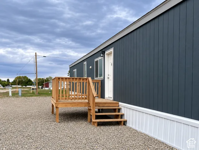 Exterior featuring dark blue-charcoal-toned vertical siding, white skirting, and an elevated wood deck with matching stairs and balustrade