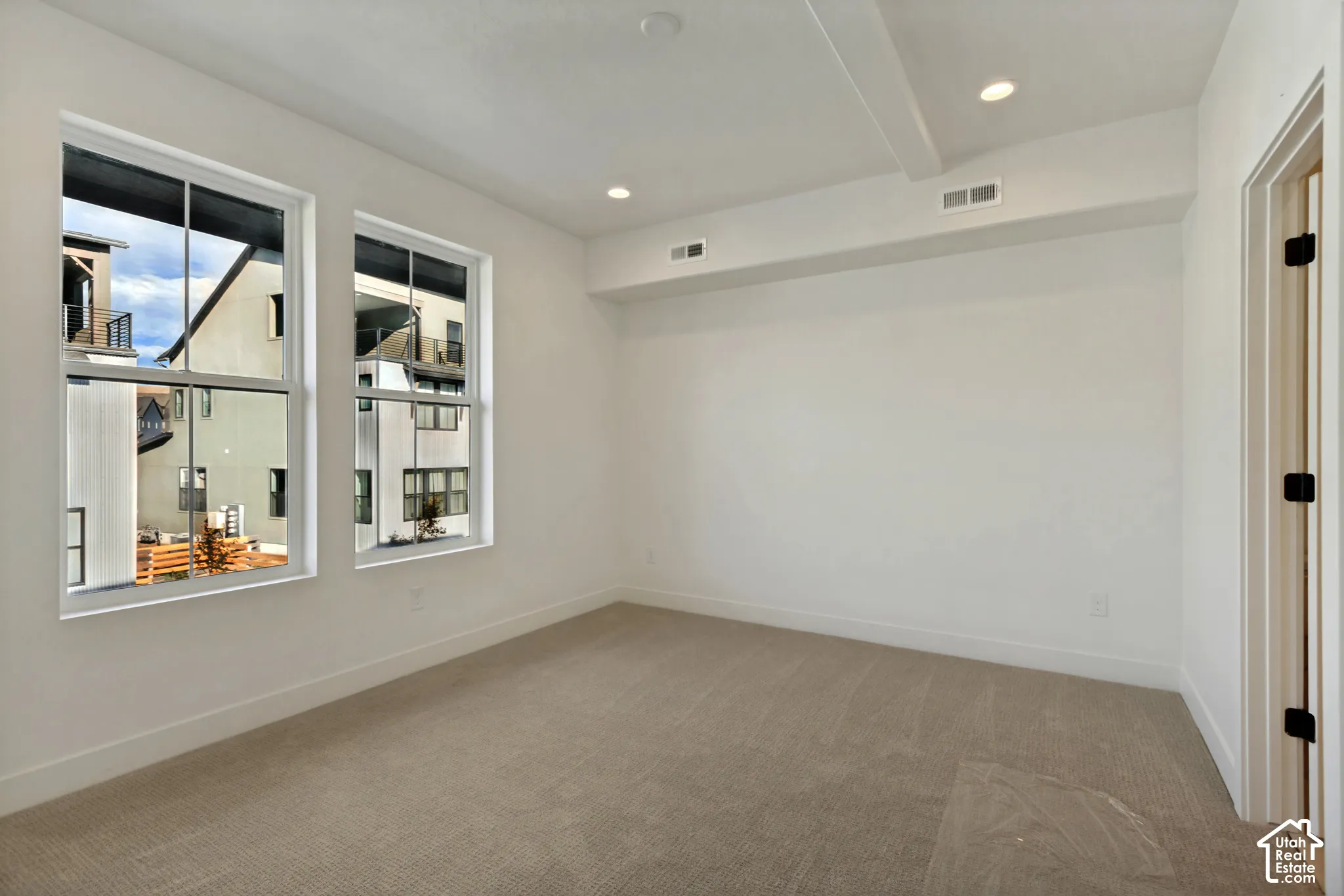 Neutral interior room featuring recessed ceiling lighting, wall-to-wall carpeting, and double-pane windows with mullions