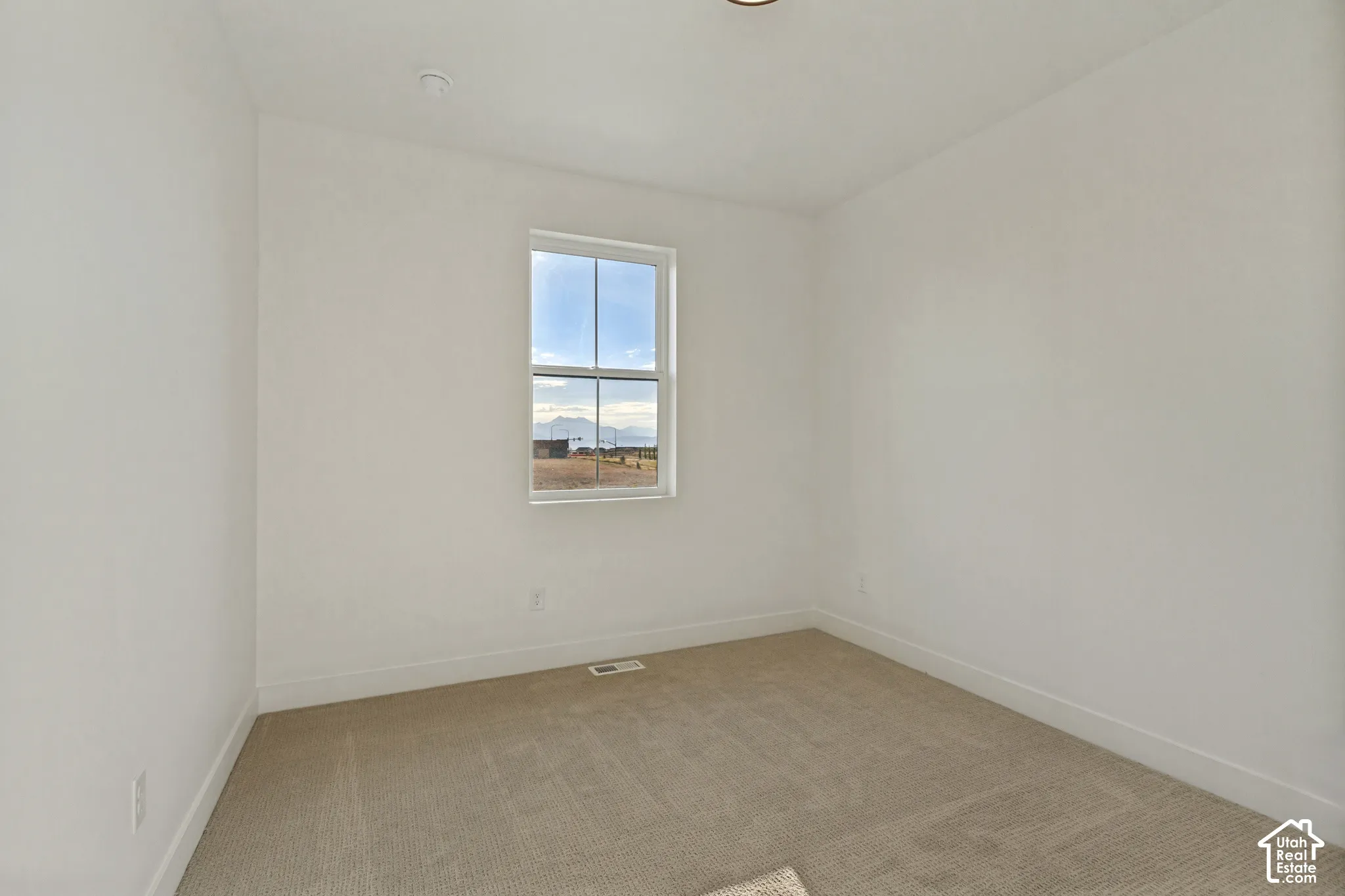 Neutral-toned wall-to-wall carpeting, crisp white walls, and a single-hung window featuring mountain scenery