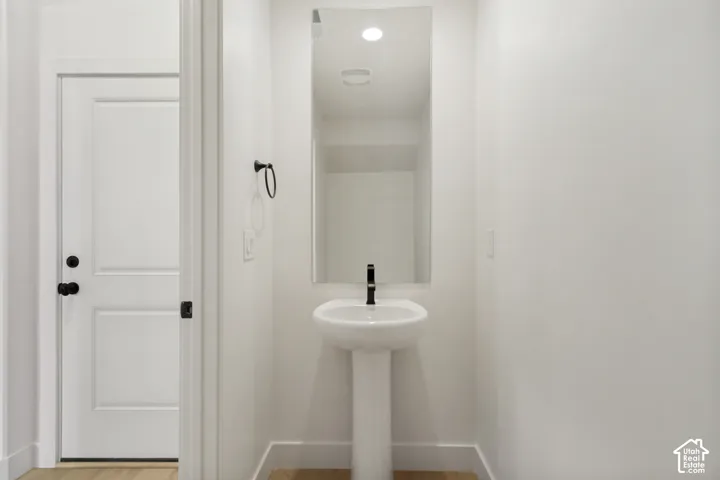 Pedestal sink featuring a matte black faucet, wall-mounted mirror, matte black towel ring, and solid-core door with matte black hardware