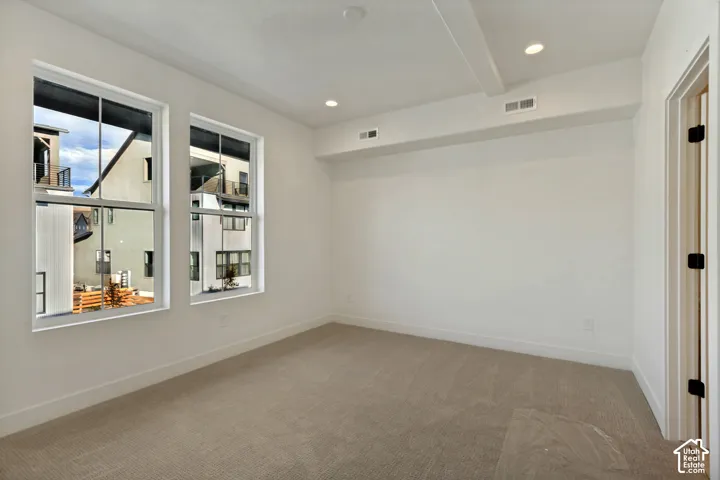 Neutral interior room featuring recessed ceiling lighting, wall-to-wall carpeting, and double-pane windows with mullions