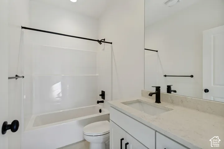 Bathroom featuring a vanity with a light-toned countertop, integrated rectangular sink, matte black faucet, white shaker-style cabinetry, and a shower-tub combination with matte black hardware