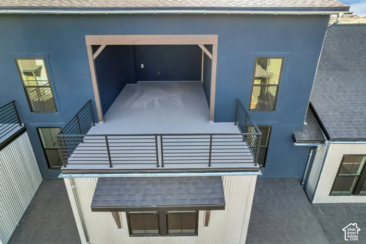 Exterior covered deck featuring dark blue smooth stucco siding, exposed wood support beams, and black metal railings