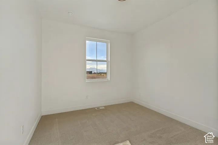 Neutral-toned wall-to-wall carpeting, crisp white walls, and a single-hung window featuring mountain scenery