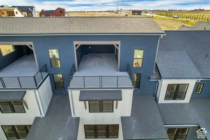 Multi-level exterior featuring dark blue stucco siding, corrugated metal accents, expansive covered balconies with horizontal railings, and dark-framed windows
