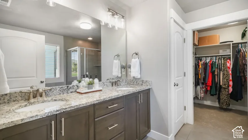 Double vanity featuring granite countertops, undermount sinks, dark-finish cabinetry, and multi-light fixtures