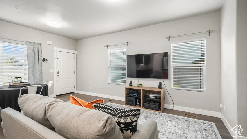 Neutral-toned interior featuring wood-finish laminate flooring, and two dual-pane windows with horizontal blinds