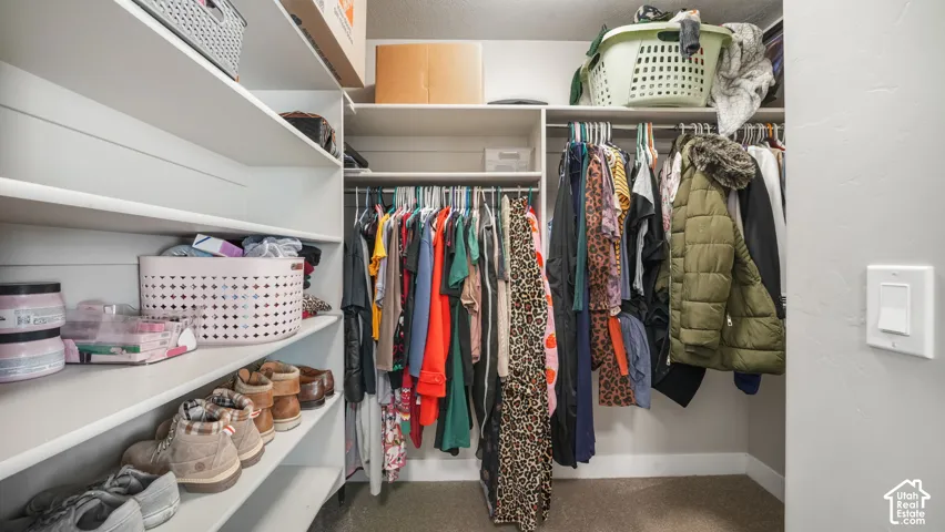 Primary walk-in closet featuring multi-tiered built-in shelving and dual hanging rods