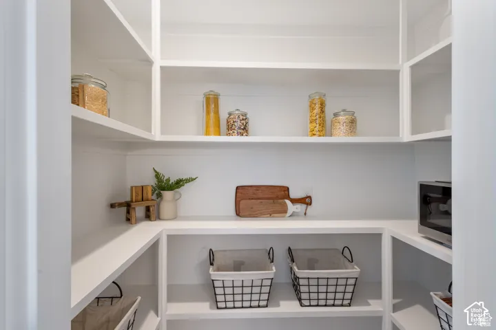 Walk-in pantry featuring white custom built-in shelving, horizontal shiplap wall detailing, and an integrated electrical outlet