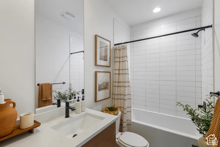 Bathroom featuring a wood-finish vanity with a stone-surface countertop, rectangular undermount sink, matte black hardware, and floor-to-ceiling white subway tile surrounding the tub