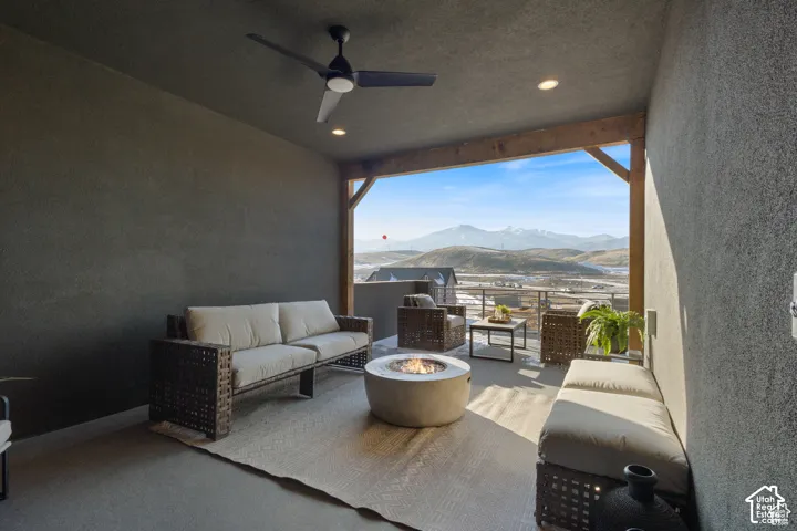 Covered patio featuring a matte black ceiling fan, recessed lighting, exposed timber beam accents, and mountain scenery