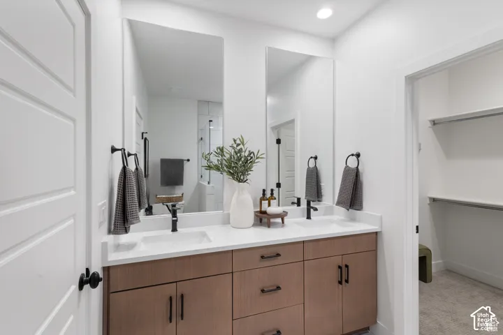 Dual-sink vanity featuring wood-finish cabinetry, white solid-surface countertops, rectangular drop-in sinks, and matte black hardware