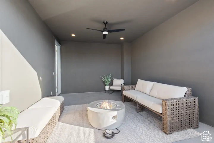 Covered patio featuring concrete flooring, charcoal-toned walls, recessed lighting, and a dark-finished ceiling fan