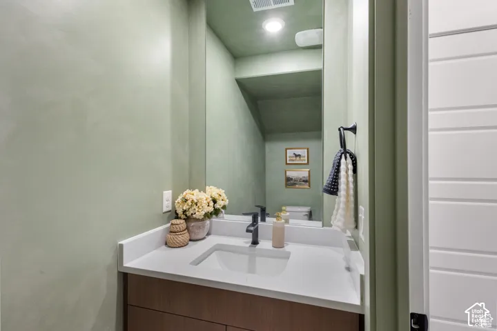 Vanity featuring a stone-composite countertop, undermount sink, dark-finish faucet, and full-height wall mirror