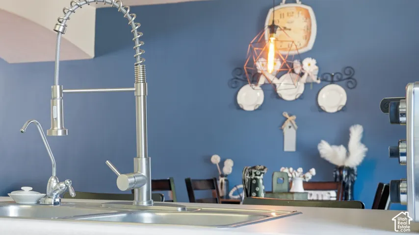 Stainless steel gooseneck faucet with integrated pull-down sprayer, dual-basin stainless steel sink, and brushed metal secondary water dispenser