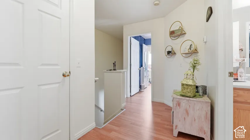 Hallway featuring wood-finish flooring, white panel doors, and a partial staircase railing