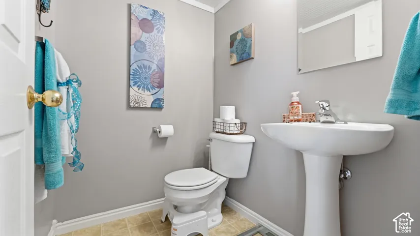 Powder room featuring a white pedestal sink with a chrome single-lever faucet, a wall-mounted mirror, and a standard-height toilet