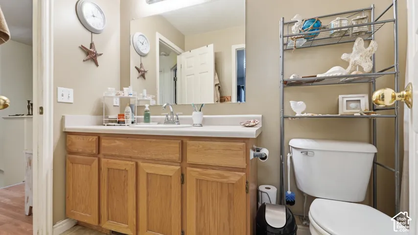 Bathroom featuring a wood vanity with raised-panel cabinetry, solid-surface countertop, integrated basin, and a large-format frameless wall mirror