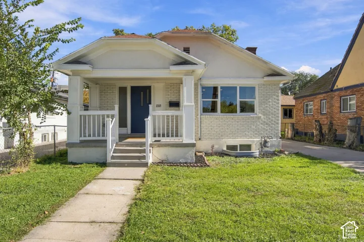 Bungalow exterior featuring a painted brick facade, covered front porch with square columns, and horizontal siding details