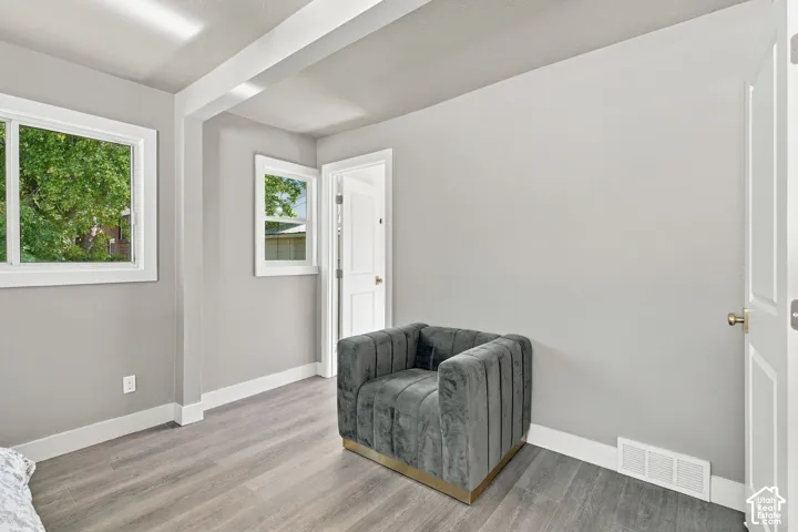 Room featuring wood-finish flooring, neutral wall paint, dual windows, and multi-panel interior doors