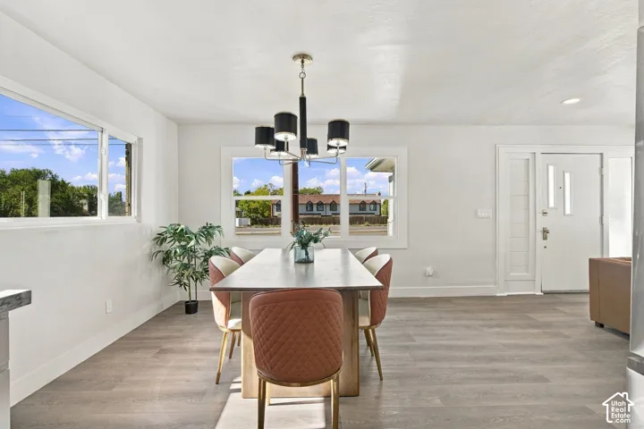 Open-concept area featuring wood-finish flooring, multi-pane windows, a five-arm modern chandelier, and a paneled entry door