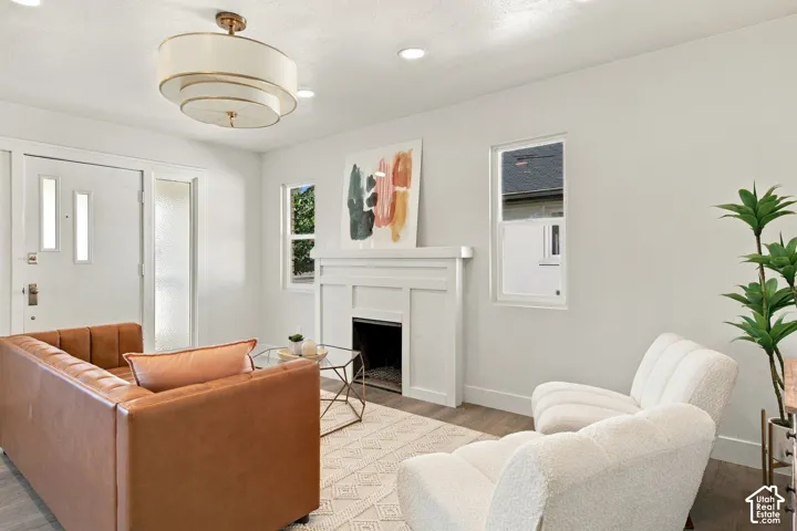 Fireplace featuring a white tiered mantle, recessed lighting, multi-tier drum chandelier, dual-pane windows, and wood-finish flooring