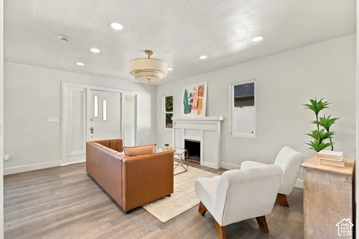 Living area featuring wood-finish flooring, recessed lighting, tiered drum pendant light, and a white fireplace mantel with a built-in hearth