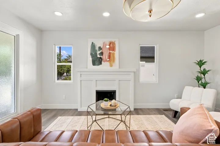 Fireplace with custom millwork surround, recessed lighting, wood-finish flooring, and modern geometric ceiling fixture