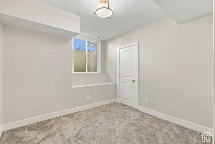 Room featuring neutral-toned carpeting, a recessed window, a multi-panel interior door, and a flush-mount drum ceiling light