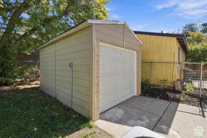 Detached storage structure featuring horizontal siding, a white garage-style door, and an exterior concrete pad
