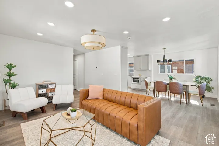 Open-concept interior featuring wood-finish flooring, recessed lighting, and tiered drum pendant lighting