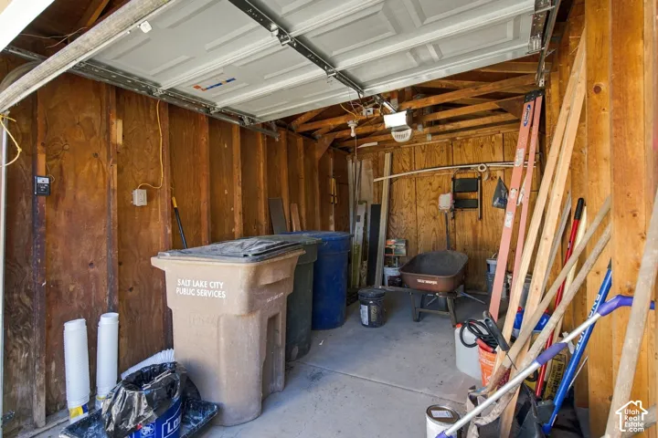Enclosed garage space featuring exposed wood-stud wall framing, a concrete floor surface, and a manual overhead sectional door