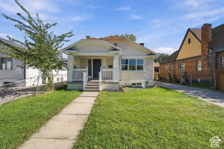 Exterior featuring light-toned brick masonry, a covered front porch with white railing, and a concrete walkway