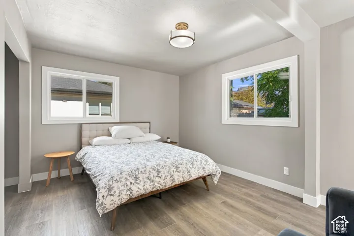 Neutral-toned interior featuring wood-finish flooring, dual sliding windows, and a semi-flush mount drum light fixture