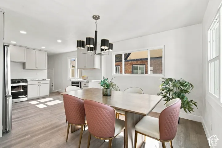 Kitchen and dining area featuring light-toned cabinetry, stainless steel appliances, wood-finish flooring, recessed lighting, and a multi-arm chandelier