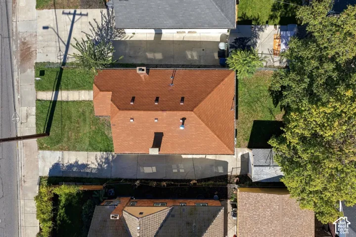Aerial view of a residential lot featuring a hipped roof, two masonry chimneys, and a concrete driveway