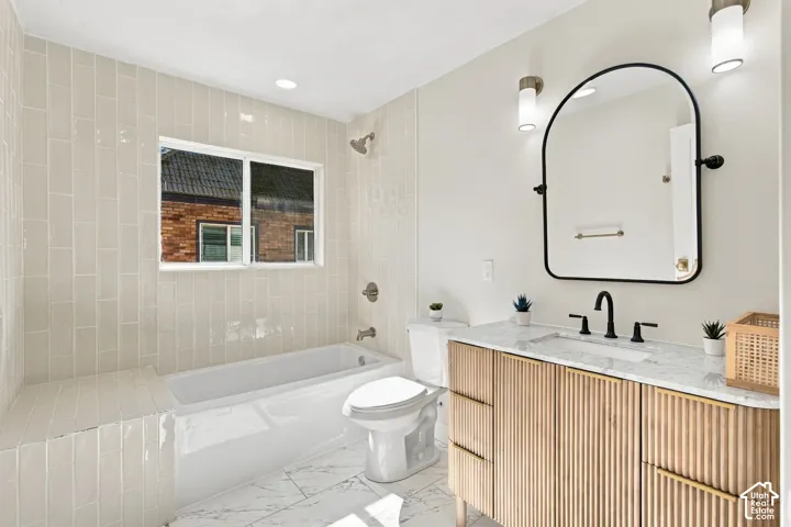 Bathroom featuring a fluted wood-finish vanity, stone-finish countertop, arch-top mirror, and floor-to-ceiling subway-style tile shower surround