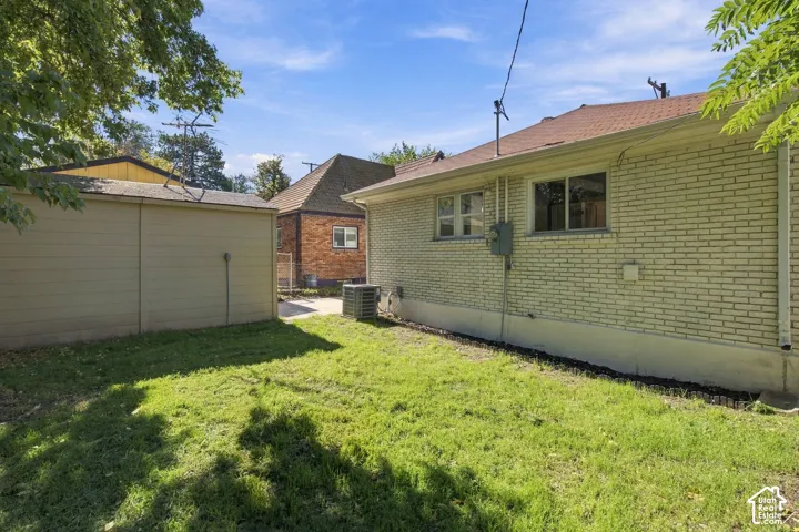Exterior featuring light-colored brick siding, a detached garage, and a grass-covered backyard