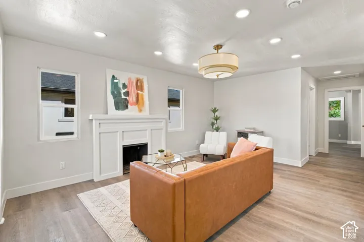 Interior space featuring wood-finish flooring, recessed lighting, a multi-tier pendant light, and a white custom-built mantel fireplace
